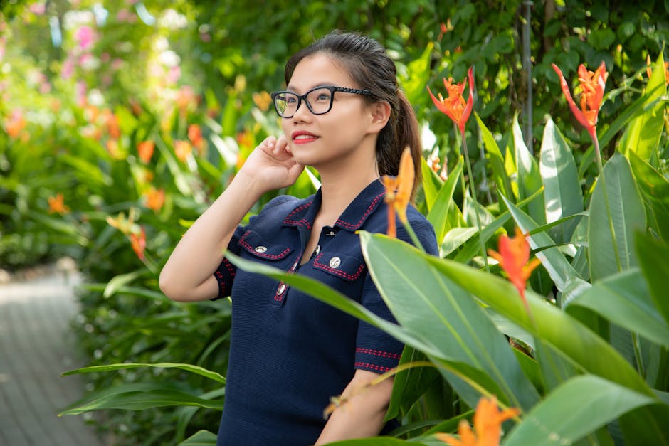 A woman in glasses standing in front of some plants